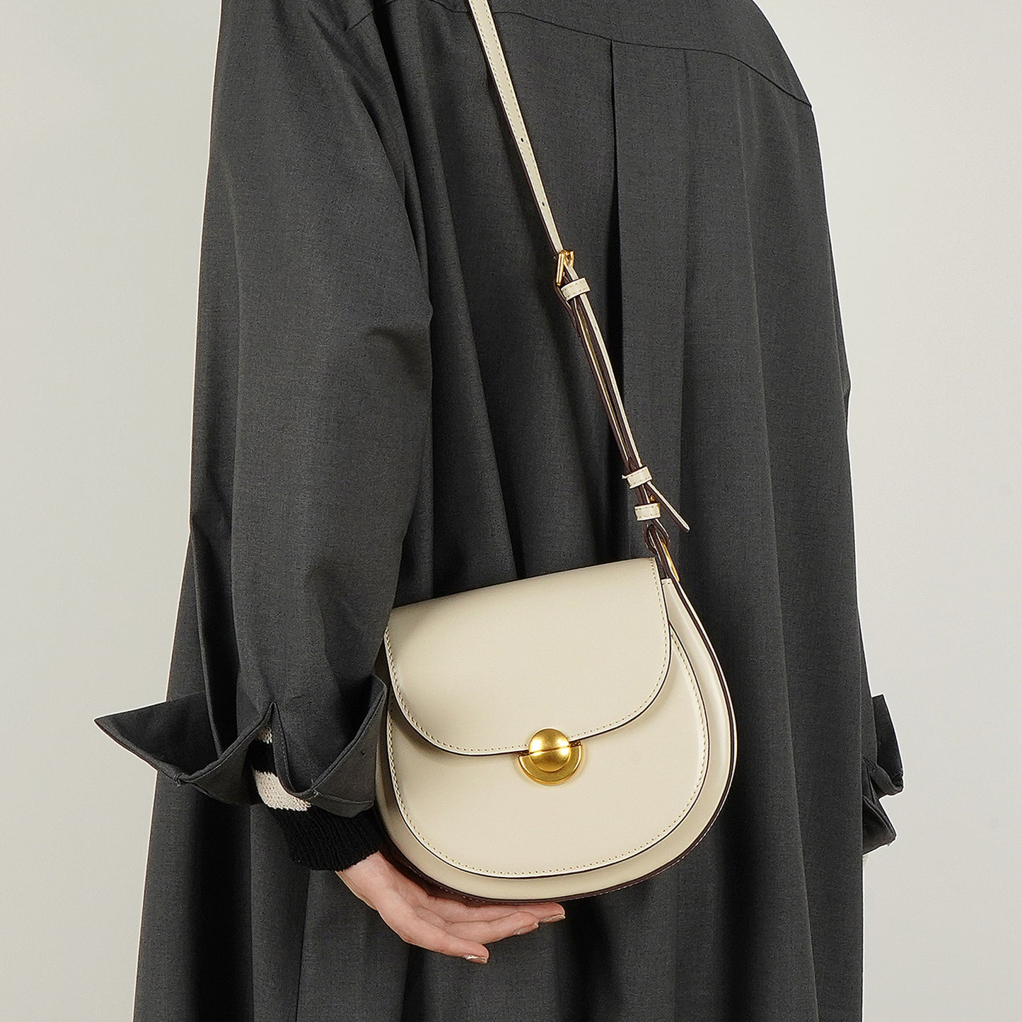 Bolsa de piel minimalista de mano con broche dorado y correa ajustable